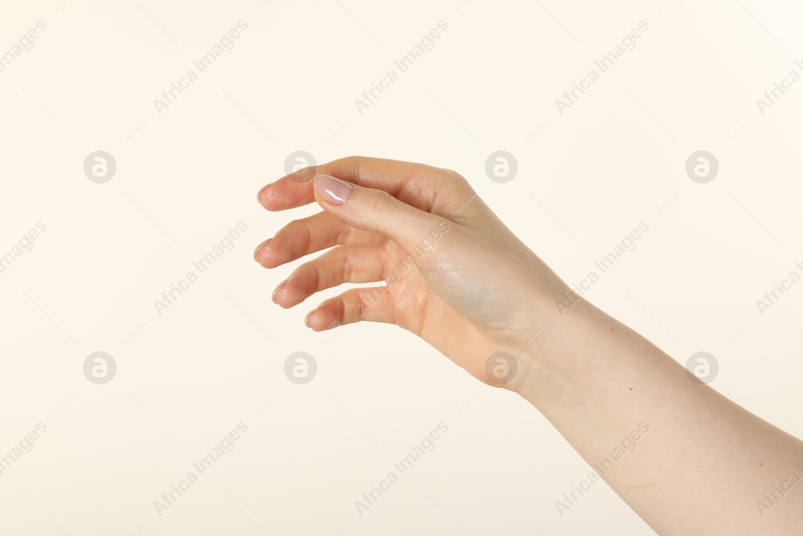 Woman holding something in hand on beige background, closeup Photo of Woman holding something in hand on beige background, closeup