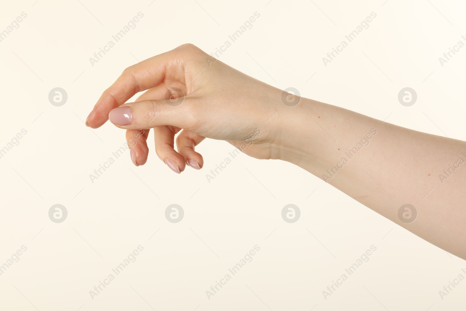 Woman holding something in hand on beige background, closeup Photo of Woman holding something in hand on beige background, closeup