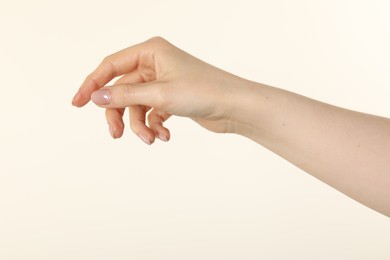 Photo of Woman holding something in hand on beige background, closeup