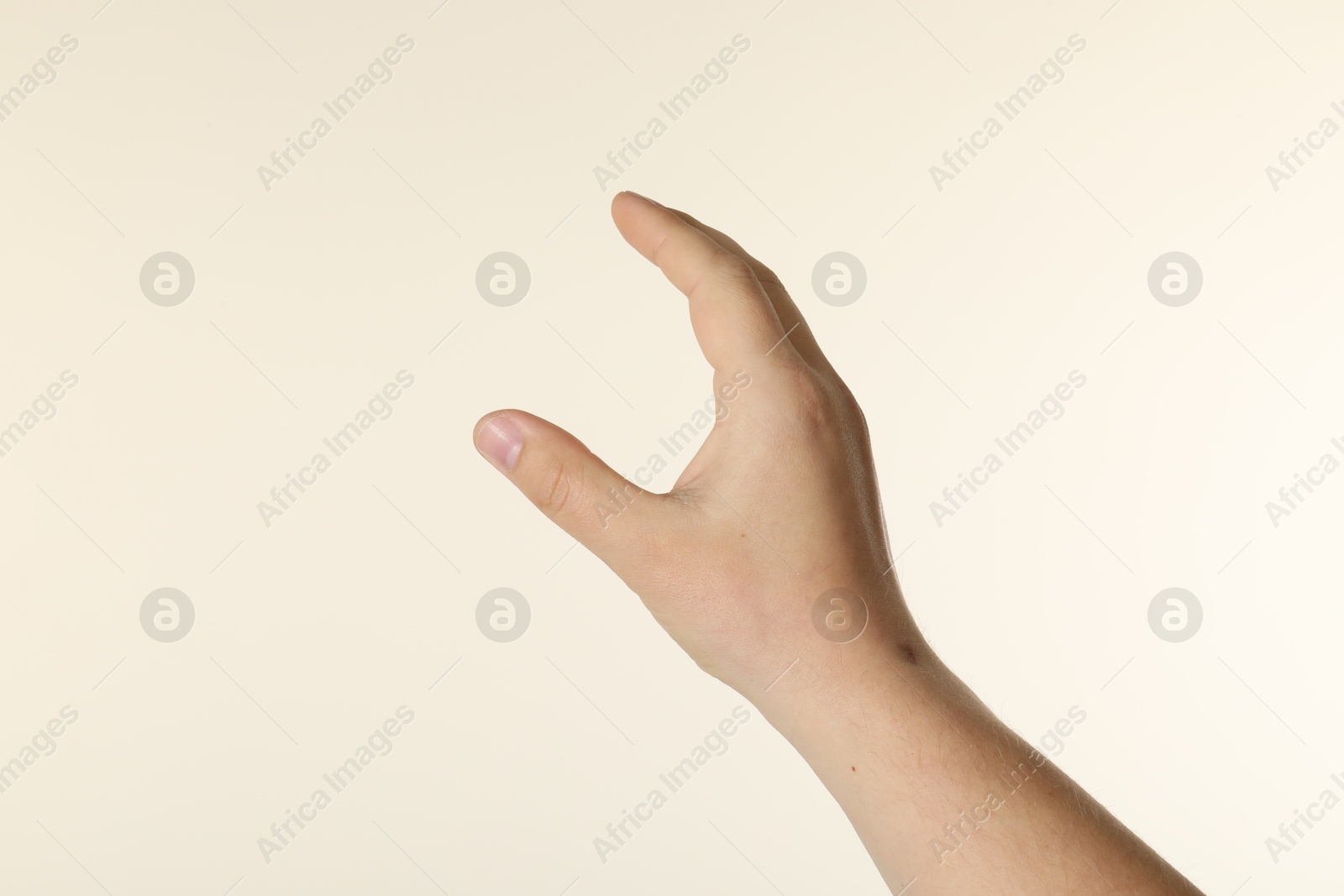Man holding something in hand on beige background, closeup Photo of Man holding something in hand on beige background, closeup