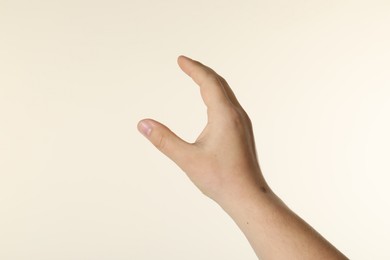 Photo of Man holding something in hand on beige background, closeup