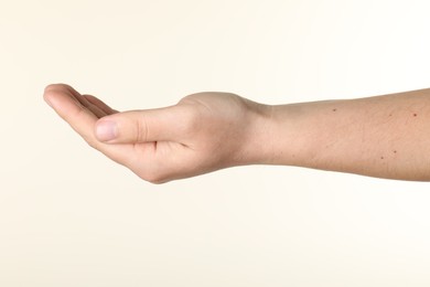 Photo of Man holding something in hand on beige background, closeup