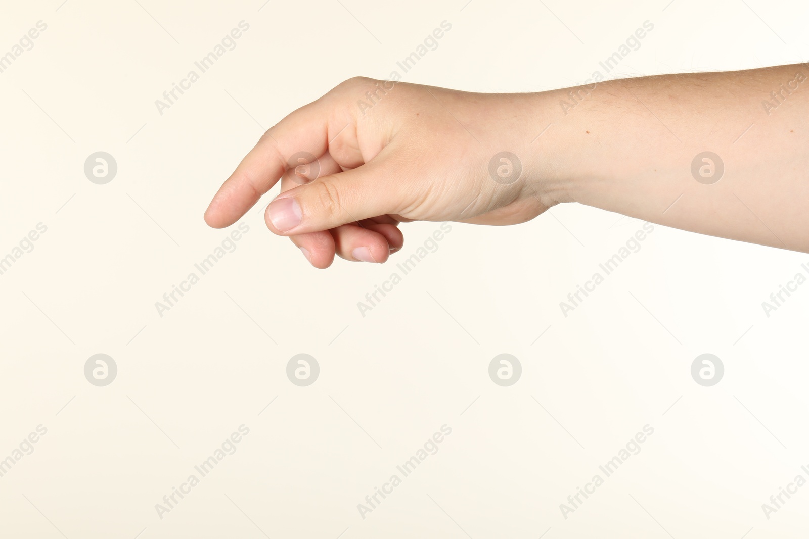 Man holding something in hand on beige background, closeup Photo of Man holding something in hand on beige background, closeup