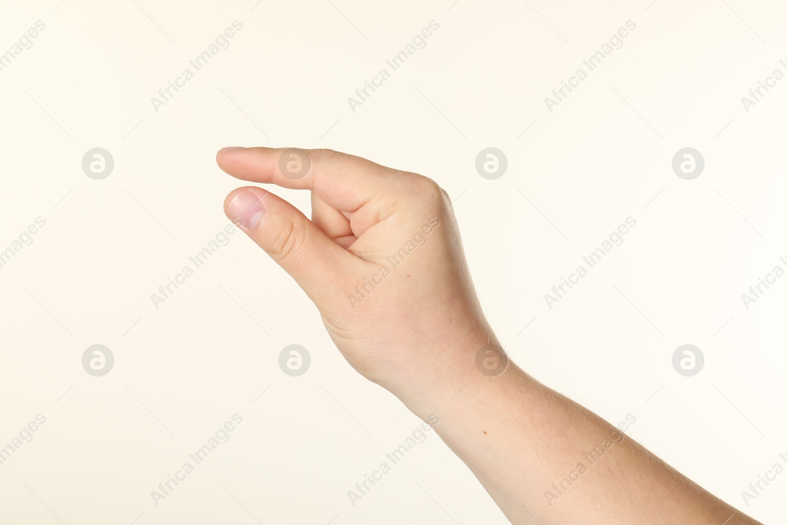 Man holding something in hand on beige background, closeup Photo of Man holding something in hand on beige background, closeup