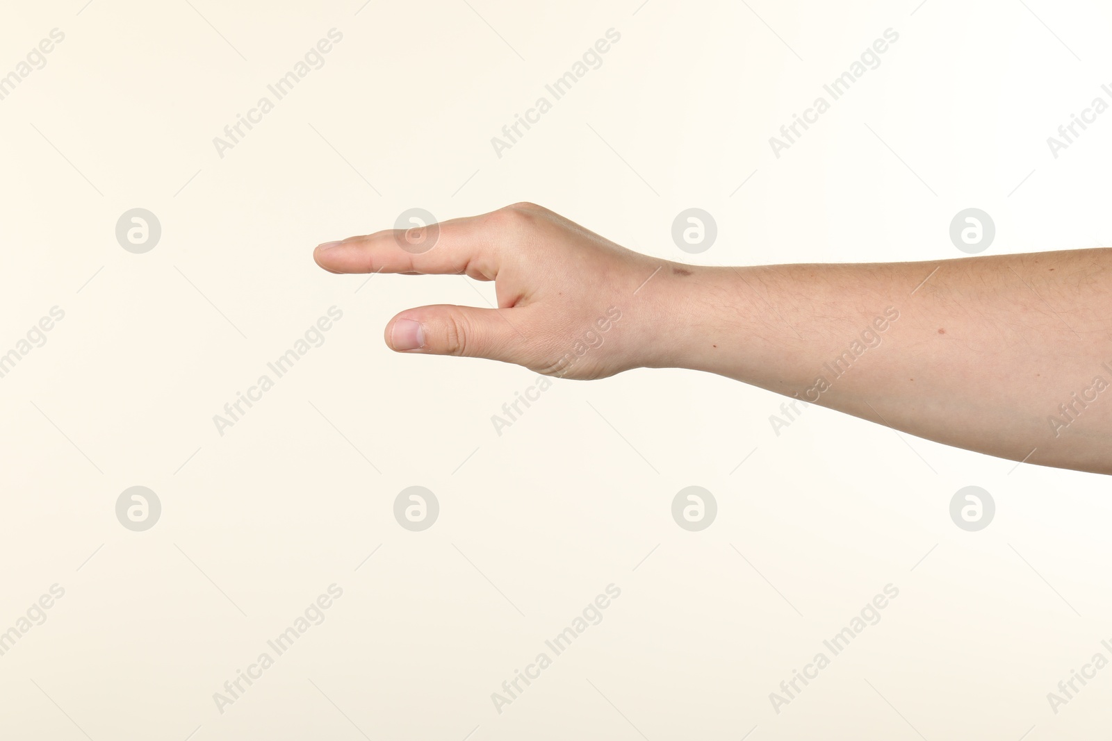 Man holding something in hand on beige background, closeup Photo of Man holding something in hand on beige background, closeup