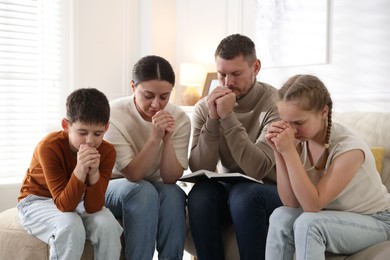 Photo of Family with Bible praying together at home