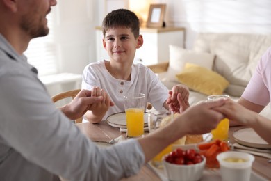 Photo of Family praying together before dinner at table indoors