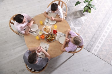 Photo of Family praying together before dinner at table indoors, above view
