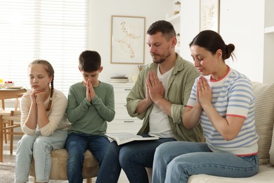 Photo of Family with Bible praying together at home