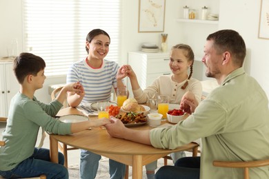 Photo of Family praying together before dinner at table indoors
