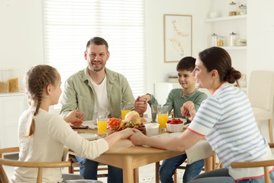 Photo of Family praying together before dinner at table indoors