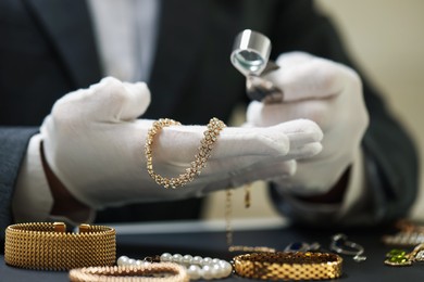 Photo of Appraiser evaluating luxury jewelry at table indoors, closeup