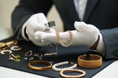 Photo of Appraiser evaluating luxury jewelry at table indoors, closeup