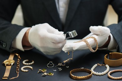 Photo of Appraiser evaluating luxury jewelry at table indoors, closeup