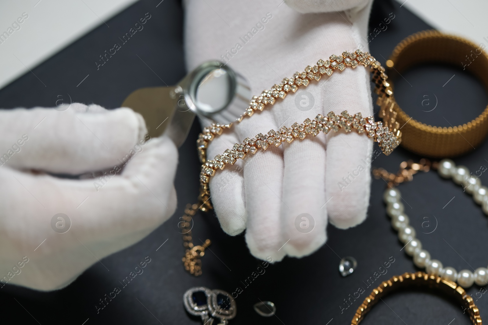 Appraiser evaluating luxury jewelry at table indoors, closeup Photo of Appraiser evaluating luxury jewelry at table indoors, closeup