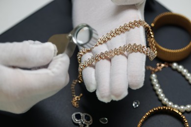 Photo of Appraiser evaluating luxury jewelry at table indoors, closeup