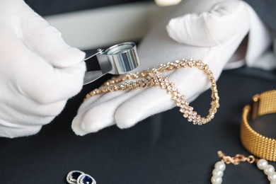 Photo of Appraiser evaluating luxury jewelry at table indoors, closeup