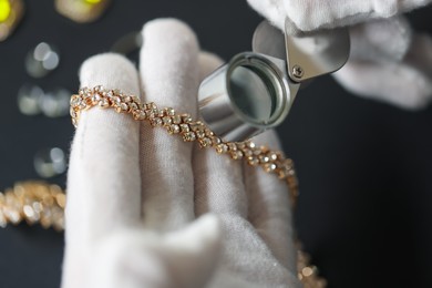 Photo of Appraiser evaluating luxury jewelry at table indoors, closeup