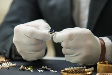 Photo of Appraiser working with luxury ring at table, closeup