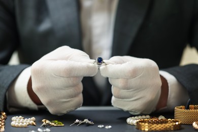Photo of Appraiser working with luxury ring at table, closeup
