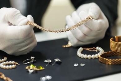 Photo of Appraiser working with luxury jewelry at table indoors, closeup