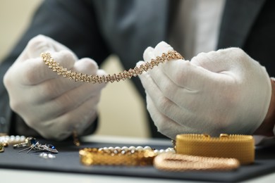 Photo of Appraiser working with luxury jewelry at table indoors, closeup