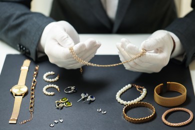 Photo of Appraiser working with luxury jewelry at table indoors, closeup