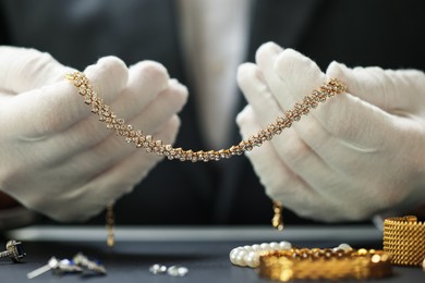 Photo of Appraiser working with luxury jewelry at table indoors, closeup