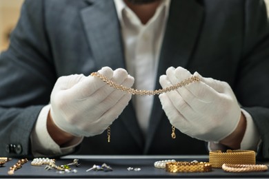 Photo of Appraiser working with luxury jewelry at table indoors, closeup