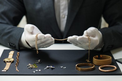 Photo of Appraiser working with luxury jewelry at table indoors, closeup