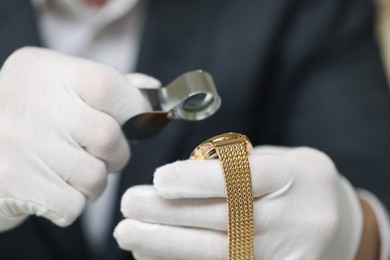 Photo of Appraiser evaluating luxury wristwatch indoors, closeup view