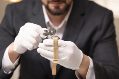 Photo of Appraiser evaluating luxury wristwatch indoors, closeup view