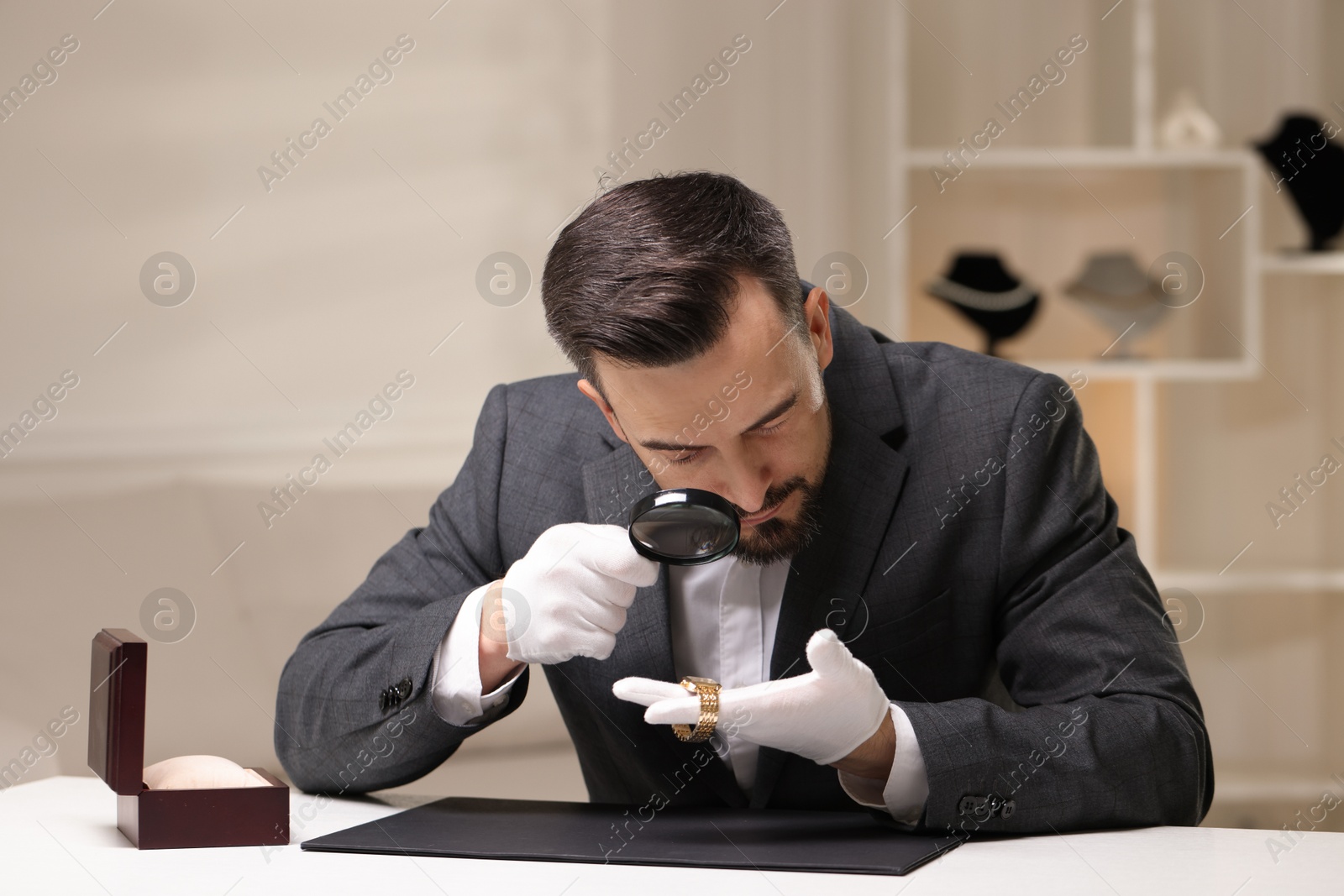 Appraiser evaluating luxury wristwatch at table indoors Photo of Appraiser evaluating luxury wristwatch at table indoors