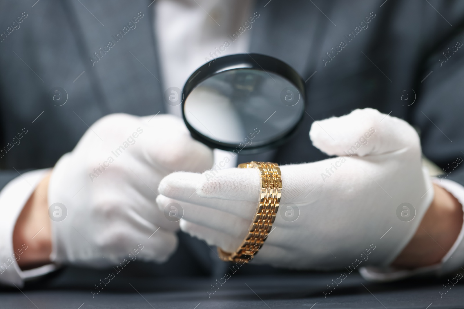 Appraiser evaluating luxury wristwatch at table indoors, closeup Photo of Appraiser evaluating luxury wristwatch at table indoors, closeup
