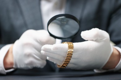 Photo of Appraiser evaluating luxury wristwatch at table indoors, closeup
