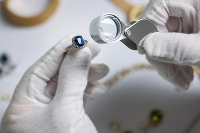 Photo of Appraiser with loupe evaluating luxury ring at white table, above view