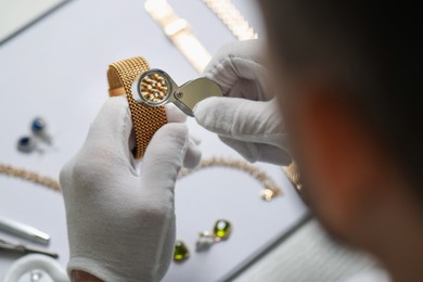 Photo of Appraiser with loupe evaluating luxury bracelet at table, above view