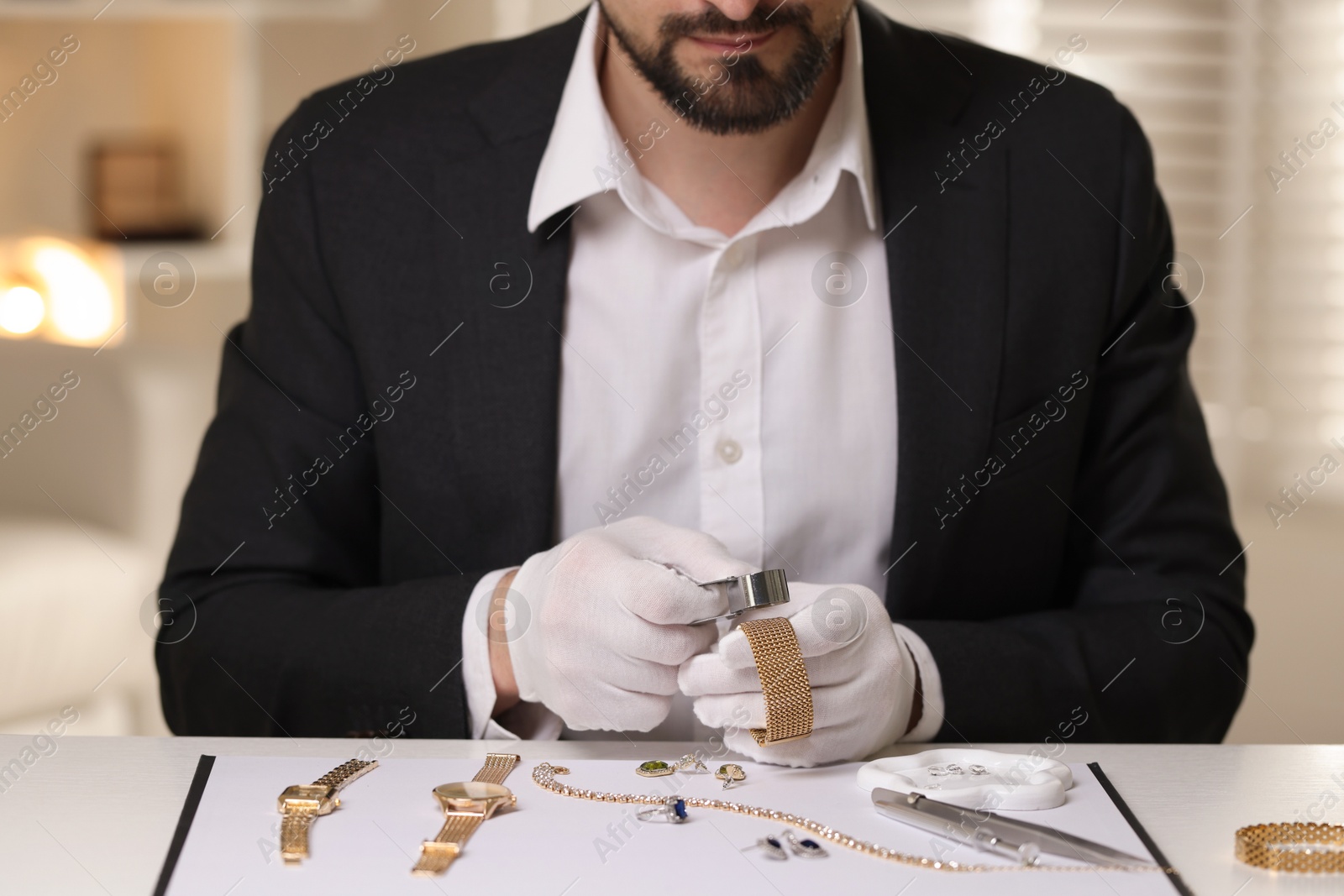 Appraiser with loupe evaluating luxury bracelet at table indoors, closeup Photo of Appraiser with loupe evaluating luxury bracelet at table indoors, closeup