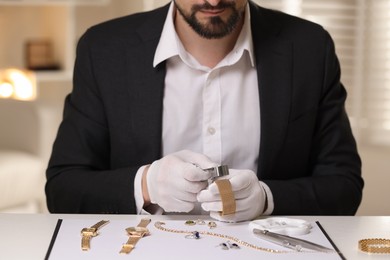 Photo of Appraiser with loupe evaluating luxury bracelet at table indoors, closeup
