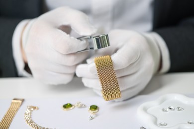 Photo of Appraiser with loupe evaluating luxury bracelet at table, closeup
