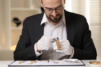 Photo of Appraiser with loupe evaluating luxury bracelet at table indoors