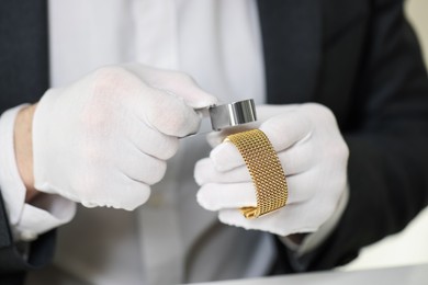 Photo of Appraiser with loupe evaluating luxury bracelet indoors, closeup