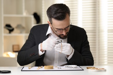 Photo of Appraiser with loupe evaluating luxury bracelet at table indoors