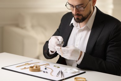 Photo of Appraiser with loupe evaluating luxury bracelet at table indoors, space for text