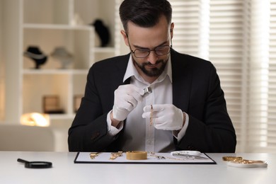 Photo of Appraiser with loupe evaluating luxury bracelet at table indoors