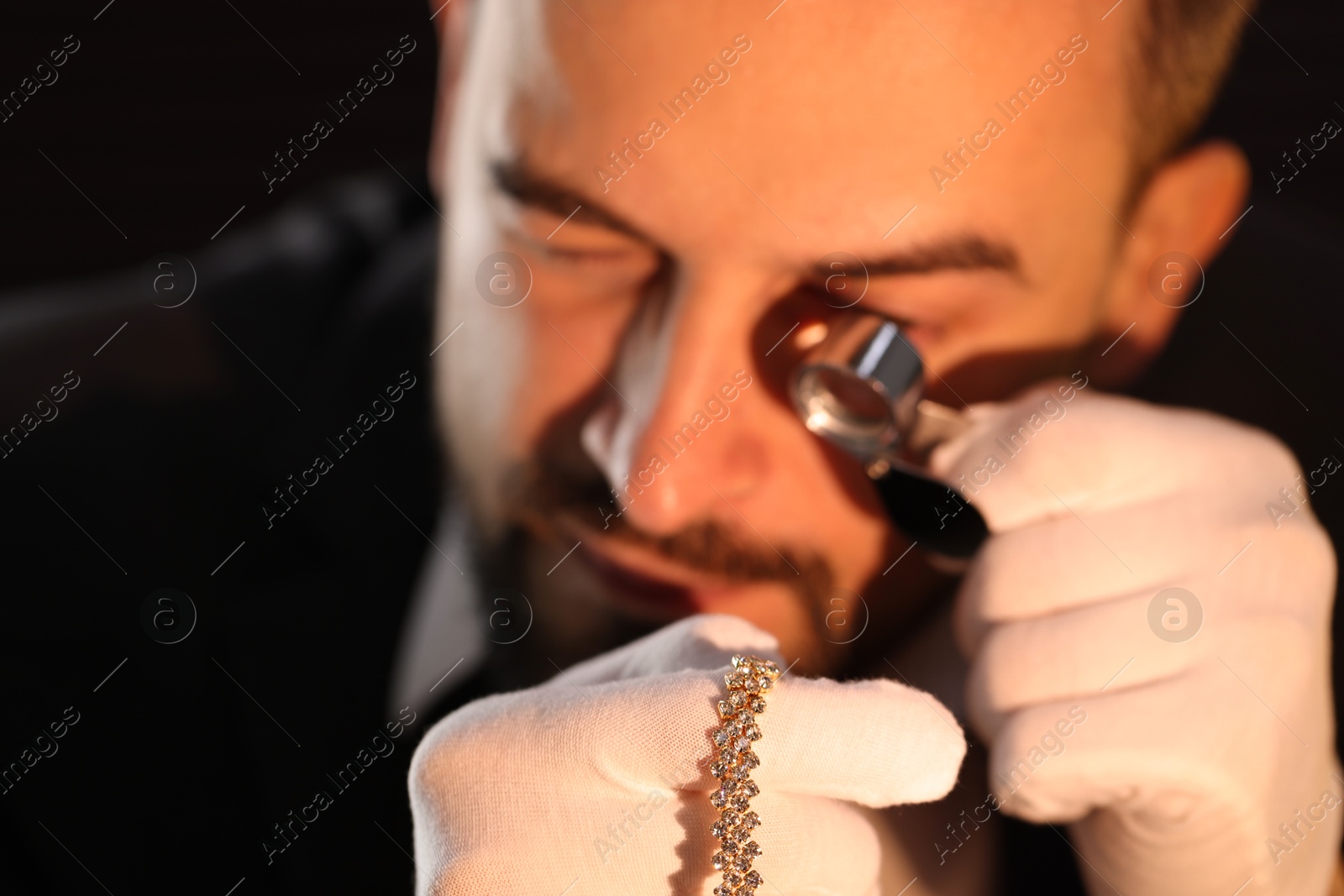 Appraiser with loupe evaluating luxury jewelry indoors, selective focus Photo of Appraiser with loupe evaluating luxury jewelry indoors, selective focus