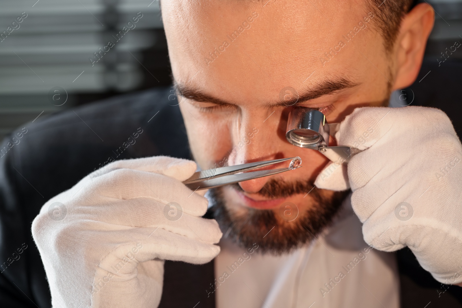 Photo of Appraiser with loupe evaluating luxury gemstone indoors