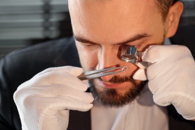 Photo of Appraiser with loupe evaluating luxury gemstone indoors