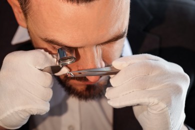 Photo of Appraiser with loupe evaluating luxury gemstone indoors