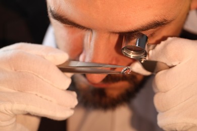 Photo of Appraiser with loupe evaluating luxury gemstone indoors, closeup